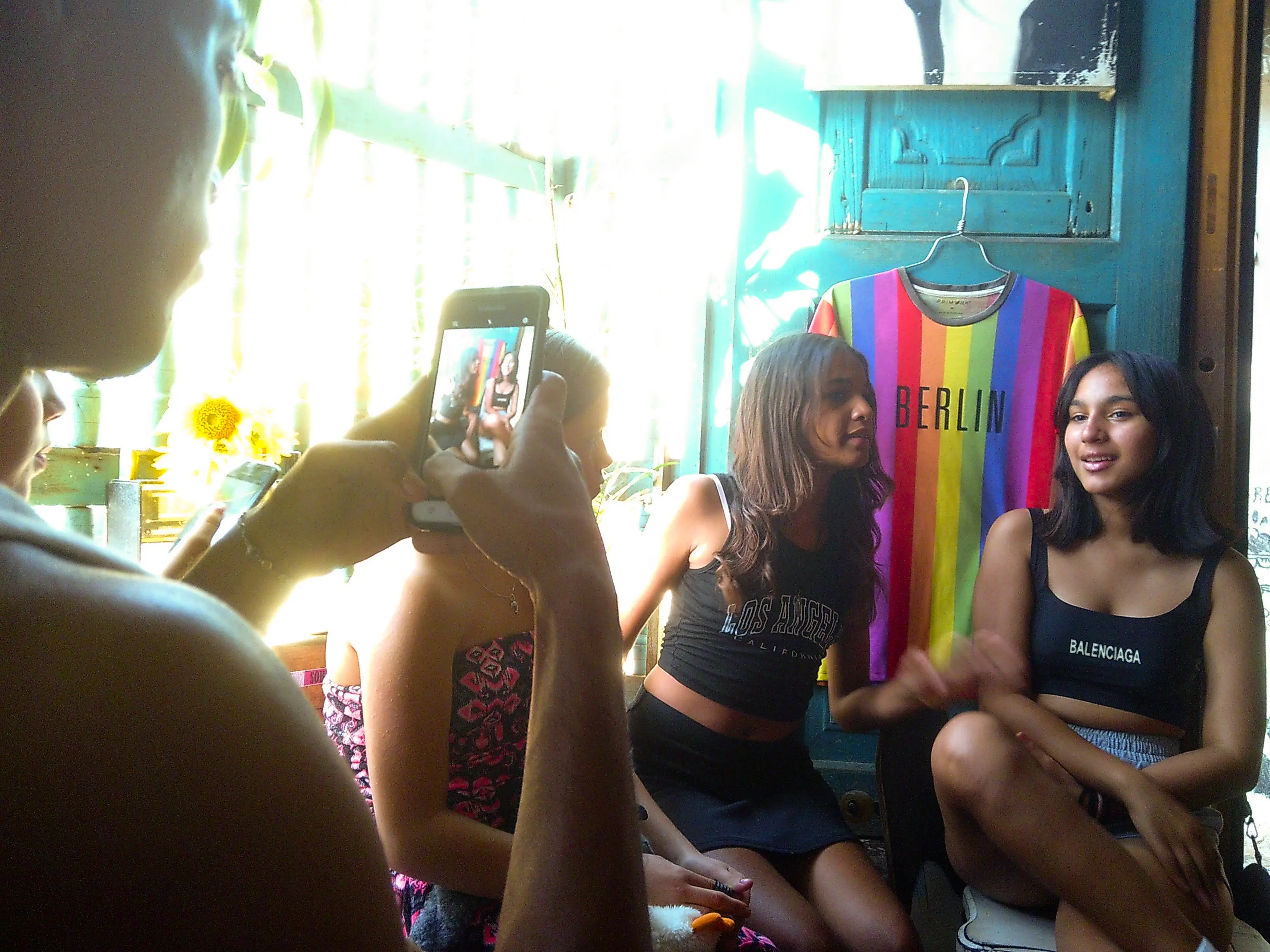 lads taking photos in a bar next to pride tshirt