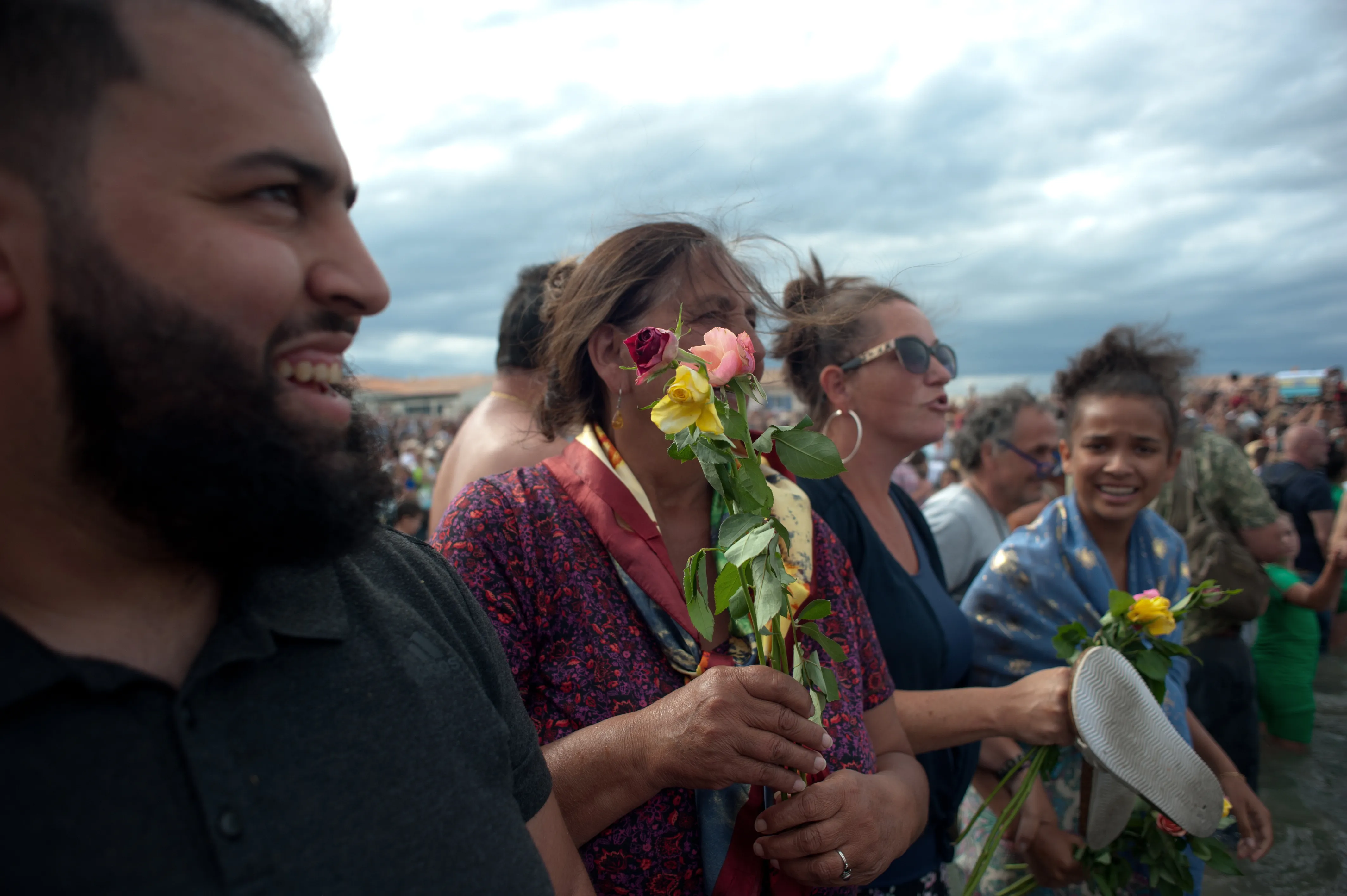 crowd with flowers wait on the beach
