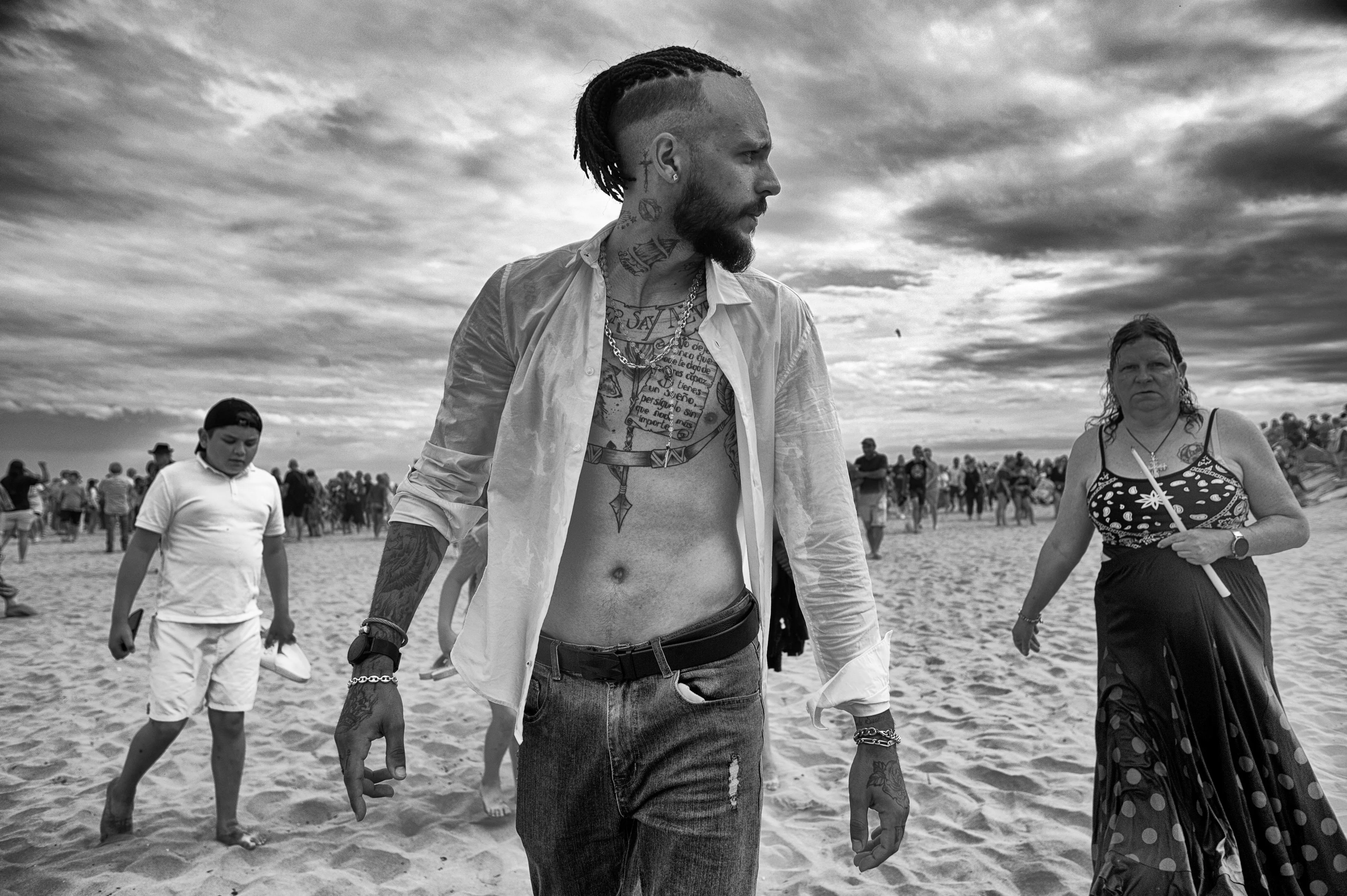 man with open shirt and tattoos and woman on the beach